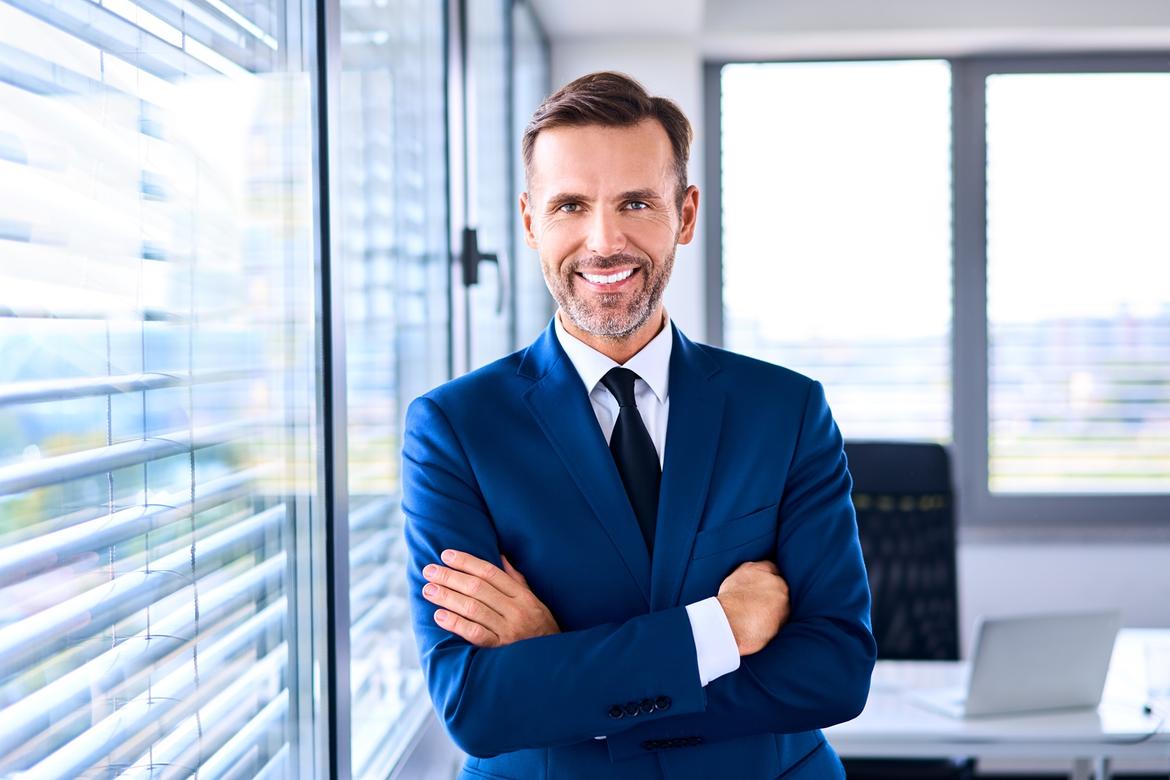 Portrait of successful businessman standing in corner office