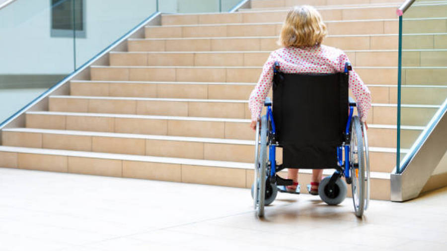 woman on wheelchair standing before stairs looking up for help